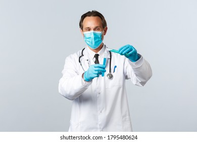 Covid-19, preventing virus, healthcare workers and vaccination concept. Smiling doctor in medical mask and gloves pouring chemical ingridient into another test-tube, conducting vaccine tests - Powered by Shutterstock