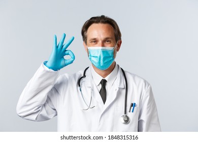 Covid-19, Preventing Virus, Healthcare Workers And Vaccination Concept. Satisfied Confident Doctor In Medical Mask And Gloves, Pleased With Patient Results, Show Okay Sign, No Problem Gesture