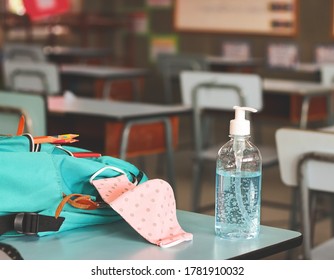 COVID-19 prevention , back  to school  and new normal  concept.Front view of  sanitizer hand gel , pink polka dots fabric mask  and  backpack with school supplies on  school desk in classroom. - Powered by Shutterstock