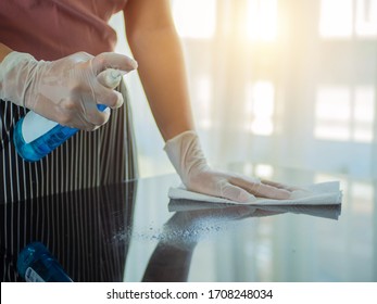 COVID-19 prevention sanitizing inside. Cleaning home table sanitizing kitchen table surface with disinfectant spray bottle washing surfaces with towel and gloves. - Shutterstock ID 1708248034