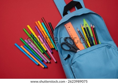 COVID-19 prevention while going back to school and new normal concept.Top view of backpack with school supplies on red background.