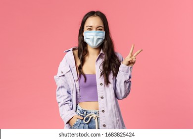 Covid19, quarantine, people concept. Optimistic, smiling happy girl in medical face mask, inside home, show peace sign, encourage stay safe during coronavirus pandemia outbreak, pink background - Powered by Shutterstock