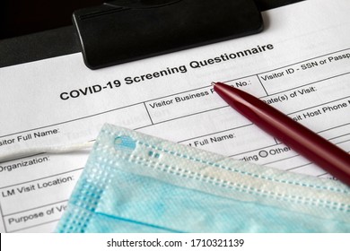 COVID-19 Screening Questionnaire form with medical mask and a pen on it. Healthcare and medical concept. Closeup
