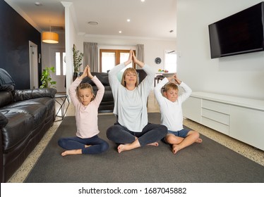 COVID-19 Shutdown. Caucasian Family Doing Yoga At Home In Quarantine. Mother, Daughter And Son Doing Meditation During Lockdown. Health, Exercise Stay At Home And Self-care For Coronavirus Isolation.