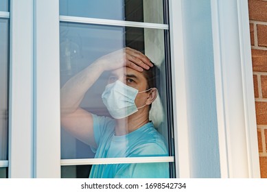 COVID-19. Sick Man Of Coronavirus Looking Through The Window And Wearing Mask Protection And Recovery From The Illness In Home. Quarantine Isolation COVID19. Sick Isolated At Home To Prevent Infection