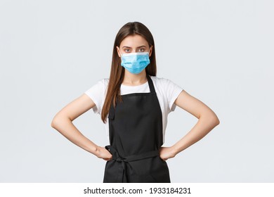 Covid-19 Social Distancing, Cafe Employees, Coffee Shops And Coronavirus Concept. Manager In Grocery Store Standing Bossy With Hands On Waist, Wearing Medical Mask, Follow Preventing Virus Protocol