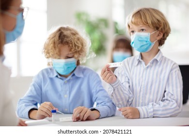 Covid-19 Test In School. Rapid Coronavirus Antigen Testing For Students In Classroom. Kid Doing Swab Test Kit In Class. Teacher In Face Mask Checking Health Exam Results. Safe Education In Pandemic.