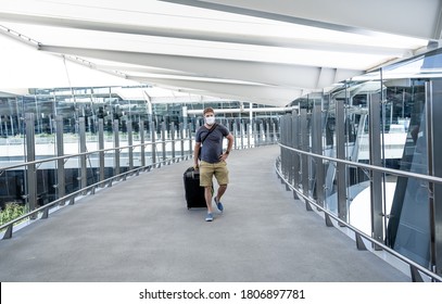 COVID-19 Travel In The New Normal. Traveler With Protective Face Mask At Airport Terminal Worried Of Quarantine Back Home. Passenger Stranded In Airport On His Travel Back To Home Country.