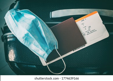 COVID-19 travel restriction due to corona virus mask wearing obligatory in airport and airplane flights to Europe, Asia. Passport, ticket and suitcase ready for holidays.