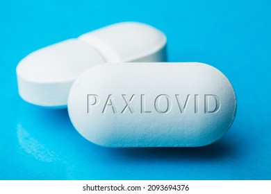 COVID-19 UK experimental antiviral drug PFE PAXLOVID,two white pills with letters engraved on side,potential experimental WHO Coronavirus cure for pandemic outbreak crisis,isolated on blue background