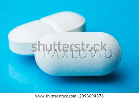 COVID-19 UK experimental antiviral drug PFE PAXLOVID,two white pills with letters engraved on side,potential experimental WHO Coronavirus cure for pandemic outbreak crisis,isolated on blue background