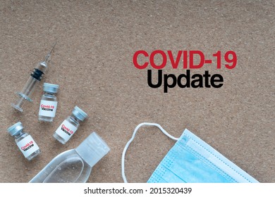 COVID-19 UPDATE Text With Face Mask, Hand Sanitizer, Syringe And Vials On Wooden Background. Covid-19, Business And Copy Space Concept

