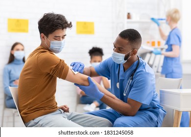 Covid-19 Vaccination. Asian Male Patient Getting Vaccinated Against Coronavirus Receiving Covid Vaccine Intramuscular Injection During Doctor's Appointment In Hospital. Corona Virus Immunization