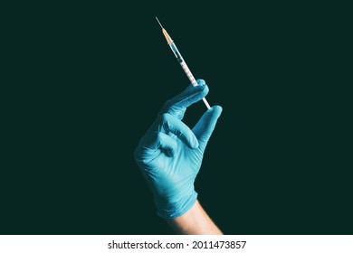 Covid-19 Vaccination Doctor Coronavirus Vaccine Syringe Held By  Nurse In Blue Medical Ppe Glove Against Black Background. First Or 2nd Dose.