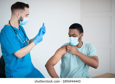 Covid-19 vaccination program. Black male patient getting coronavirus vaccine shot on visit to physician at health centre. African American guy being immunized against global virus