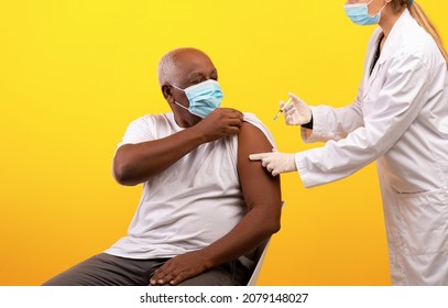 Covid-19 Vaccination. Senior Black Male Patient Getting Coronavirus Vaccine Shot On Visit To Physician Over Orange Studio Background. Elderly African American Man Being Immunized Against Covid