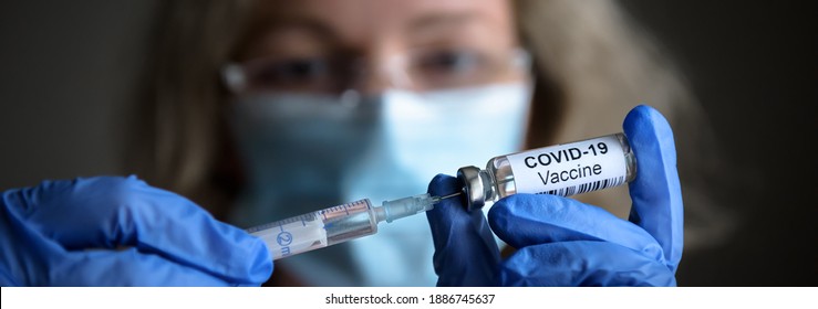 COVID-19 vaccine in doctor’s hands, panoramic view of syringe and vaccine bottle. Nurse holds vaccine vial in lab close-up. Concept of corona virus, vaccination, injection, shot, EU, USA, pandemic. - Shutterstock ID 1886745637