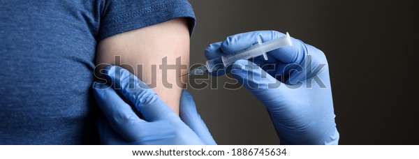 COVID-19 vaccine jab, doctor in gloves holds syringe\
and makes injection to woman patient. Prevention of coronavirus,\
smallpox or influenza. Concept of jab from corona virus, monkey pox\
and flu.