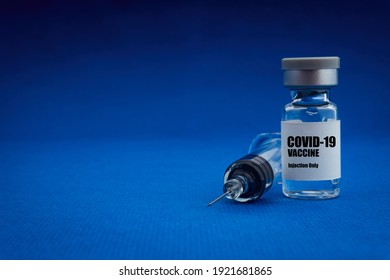 COVID-19 VACCINE text with vial and  syringe on blue background. Covid-19 or Coronavirus Concept 
