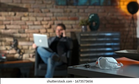 Covid-19 Virus Danger - Businessman Working At Safety Of Home Office Leaving Virus Protective Mask On Desk.