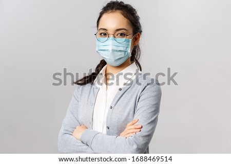 Covid19, virus, health and medicine concept. Portrait of young confident professional asian nurse, taking care of patients, wearing medical mask during quarantine coronavirus, cross hands chest