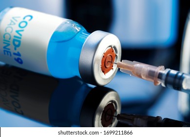 Covid-19 Written vaccine bottle with a blue liquid and taking the vaccine from it with a syringe on a laboratory like background.