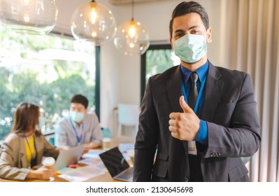 Covid-19. Young People With Face Masks Back At Work In Office After Lockdown.Asian Small Business Startup  Brainstorm Meeting With Laptop And Chart Paper Everyone Mask For Covid19 Protection Corona.