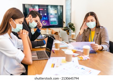 Covid-19. Young People With Face Masks Back At Work In Office After Lockdown.Asian Small Business Startup  Brainstorm Meeting With Laptop And Chart Paper Everyone Mask For Covid19 Protection Corona.