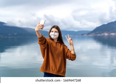 COVID-19 Young Woman In A Medical Mask Takes Selfie On The Street Of European City. Travel Consept 2020