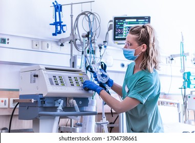 COVID19/2019-ncov concept: nurse, wearing a surgical mask, checks the settings of a mechanical ventilation machine, which is seen in the foreground. therapy used for lung breathing, in intensive care