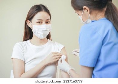 Covid-19,coronavirus hand of young woman nurse,doctor giving syringe vaccine, inject shot to asian arm's patient. Vaccination, immunization or disease prevention against flu or virus pandemic concept. - Powered by Shutterstock