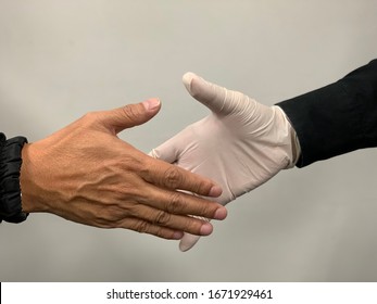 COVIT 19: Handshake Isolated On White Blackground, Two Person Handshake, A Person Wearing Rubber Gloves For Protection COVID 19 Or COLONA, New Virus Which Spreading Throughout The World