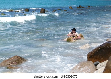 A Cowardly Man On Vacation Who Cannot Swim In The Sea Water Near The Shore, Holds A Stone, With A Bad Tan, Posing,