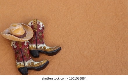 cowboy boots and hat laying on a textured brown background with writing space