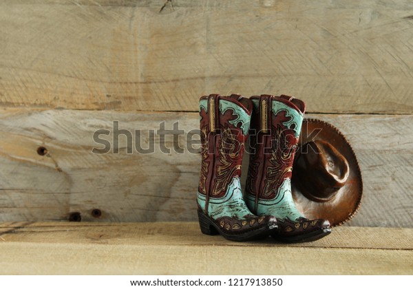 cowboy boots and hat on a natural wood background\
with writing space