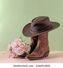 Cowboy boots shoes and hat and bouquet of rose flowers on green background minimal creative concept symbol of wild west america usa texas farm and party.