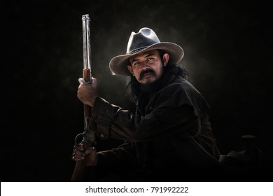 A Cowboy Carrying A Rifle On A Black Background.