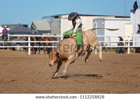 A cowboy competing in the bullriding competition at a country rodeo