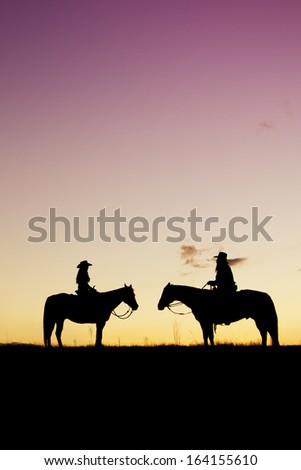 Cowboy and cowgirl silhouette at colorful sunset