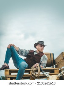 Cowboy farmer man in country side wearing western cowboy hat. American Male model in countryside on farm. Men retro fashion, vintage vogue, brutal male model.