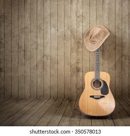 Cowboy hat and guitar against a wooden background.