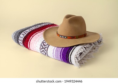 Cowboy hat on a folded Southwestern blanket with a beige background