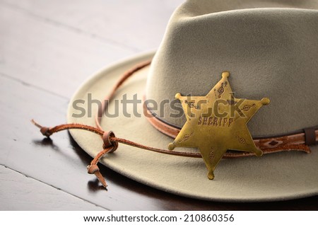 Cowboy hat with Sheriff badge on wooden background in horizontal format with selective focus