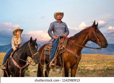 A Cowboy And His Son On Horseback Looking Over Their Ranch Lands