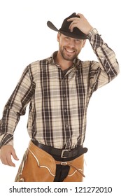a cowboy in his western gear with a smile on his face holding on to his hat.