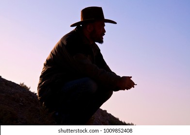 Cowboy man sitting, Adult Asian man in Hat, Silhouetted, smoking