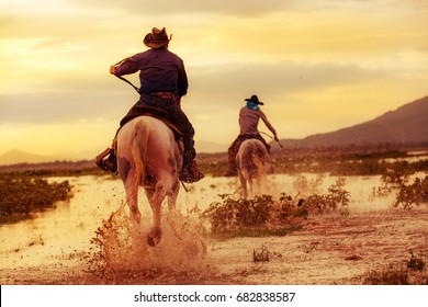 Cowboy On Horseback On Water And Mountain Background