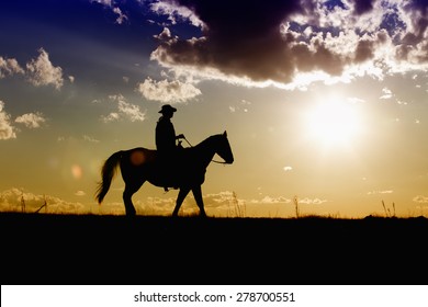 Cowboy riding his horse along the range on a colorful afternoon sunset