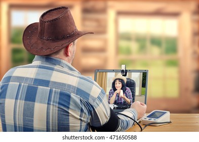 Cowboy Sitting At Wooden Desk Takes Blood Pressure During Internet Session With Virtual Doctor. He Suffers Hypertension. Rural Doctor Suggests A One High Blood Pressure Medication  To Treat Him