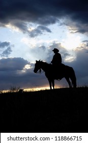 Cowboy,on Horseback, Silhouetted Against Dawn Sky